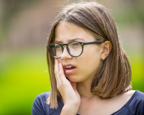 Pretty caucasian young teenage girl have a toothache.